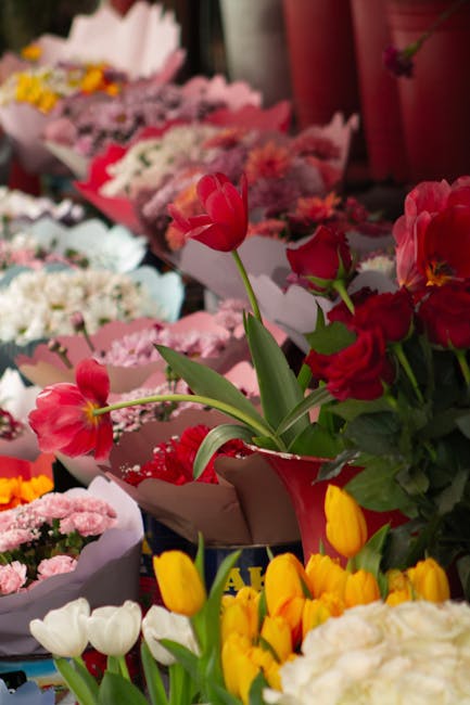 A vibrant display of fresh flowers arranged for bouquet delivery at Rush Green Road florist. Prominent in the foreground are red tulips and pink tulips with elongated green stems and fresh petals, som