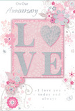 This tender anniversary card combines soft colour and gentle texture in a way that mirrors a pastel flower arrangement arriving at a doorstep in Rush Green. At its heart, the word LOVE appears in large, raised letters, each one outlined with a fine dusting of glitter that catches the light with a delicate shimmer. The slightly embossed surface makes the word pleasantly tactile, encouraging a moment's pause to trace the contours. The letters rest on a blush-pink block that glows softly against the lighter pink background, giving the card a warm focal point. Surrounding this centrepiece is a flowing pattern of stylised flowers and leaves, drawn with the kind of care a florist at Flower Delivery Rush Green might bring to planning an anniversary bouquet. The blossoms are depicted in blush, pearly white, and subtle silver-grey tones, with fine linework and gentle shading that evoke the softness of real petals. The background wash of pale, powdery pink keeps the overall feel bright and serene, allowing the tiny glitter-kissed highlights and occasional silver details to stand out. Delicate swirls, curving stems, and filigree-like flourishes weave through the floral design, creating a sense of light movement, like petals drifting in a soft breeze along nearby green spaces. An elegant script message, marking the anniversary and reaffirming enduring love, is printed in graceful, handwritten-style typography beneath or beside the floral motif. Altogether, the card feels calm, romantic, and thoughtfully made-an ideal companion to hand-delivered anniversary flowers, capturing the sentiment of shared years and cherished memories in this close-knit Rush Green neighbourhood.